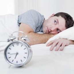 Man in bed with alarm clock